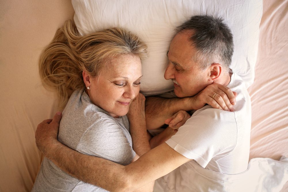 Senior couple sleeping together in bed. Senior couple sleep together on one pillow.
