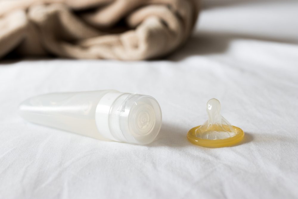 showing lubricant in the container and condom in the bed room 