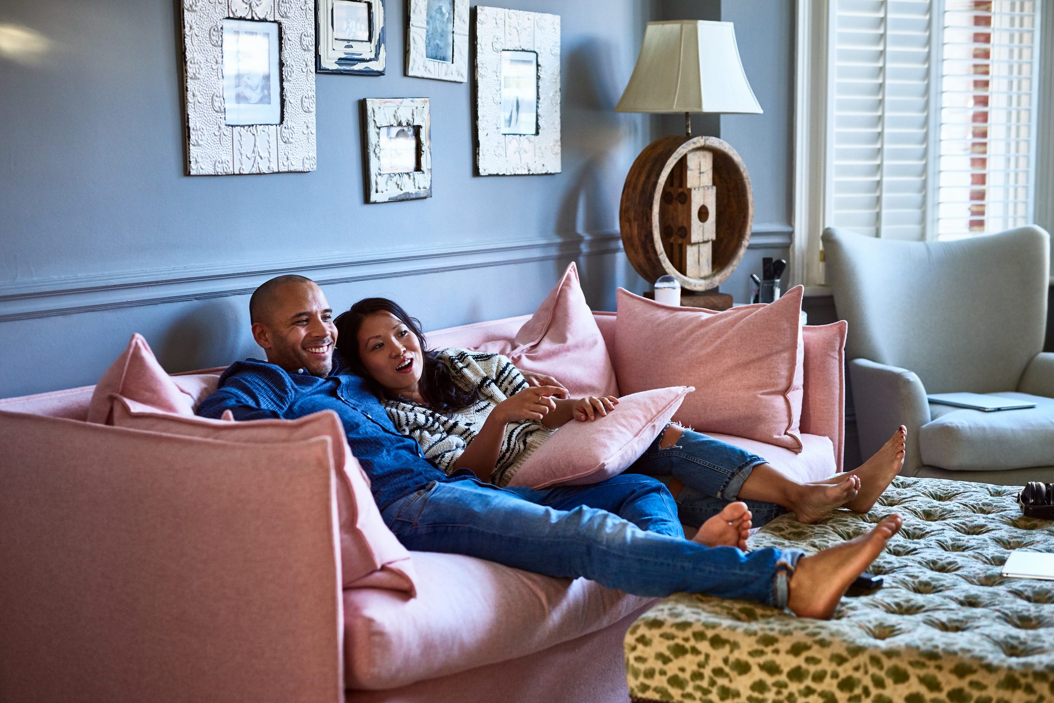 couple sitting on couch at home relaxing and laughing together