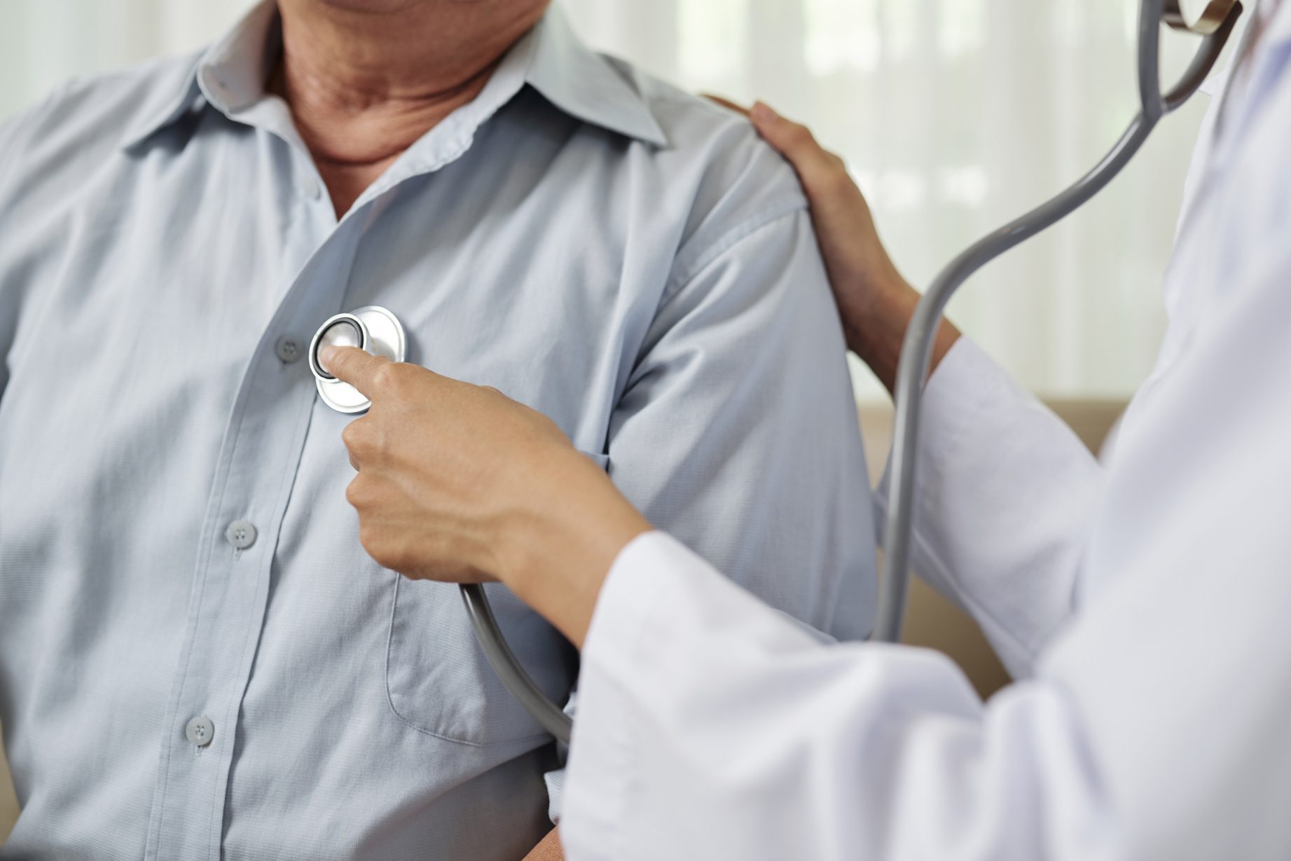 Doctor listening to senior breathing man