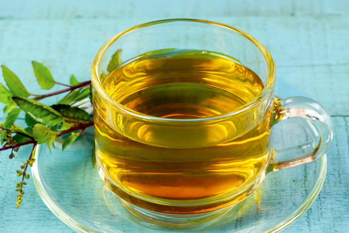 holy basil tea in a cup with leaves next to it