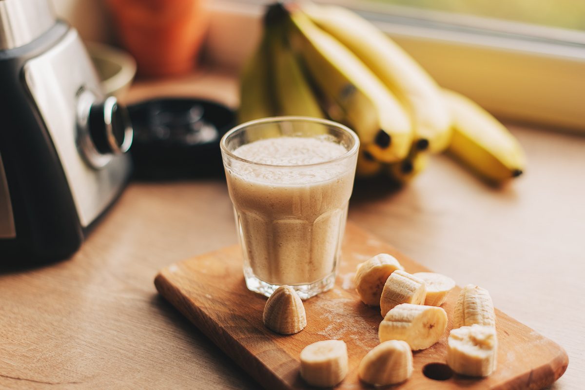 banana smoothie with cut pieces of banana next to it on a chopping board