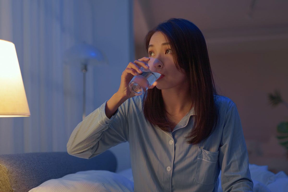 woman drinking glass of water at night