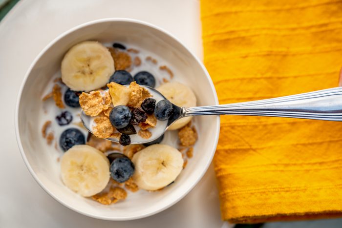 Blueberry oat flake cereal with bananas and spoonful of cereal held above the bowl