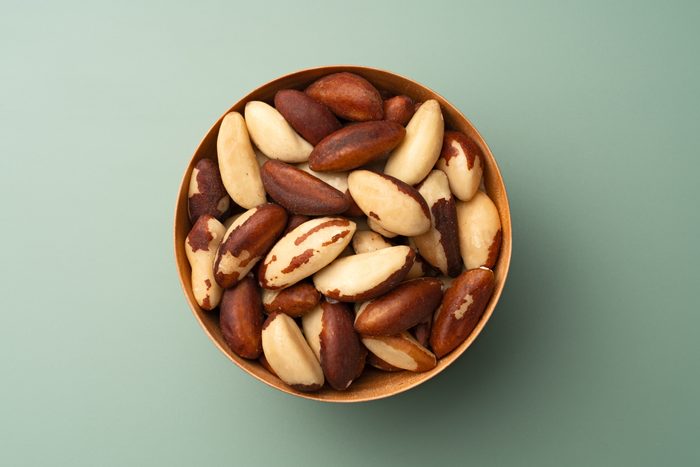 Brazil Nuts in Wooden Bowl on Green Background