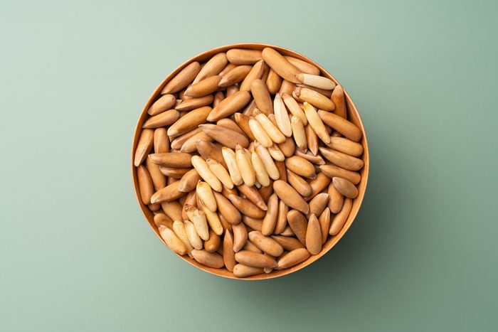 Shelled Chilgoza Pine Nuts in Wooden Bowl on Green Background