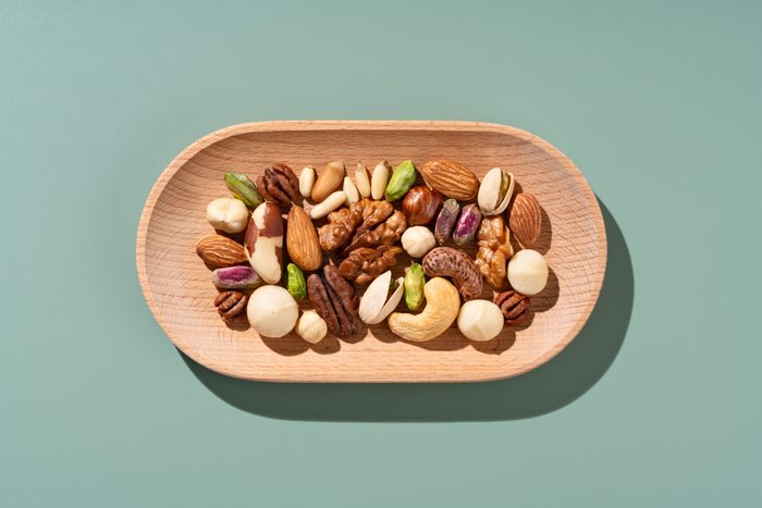 Mixed Nuts in Wooden Dish on Green Background