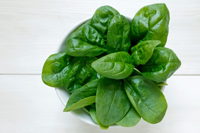fresh baby spinach leaves on white wooden background