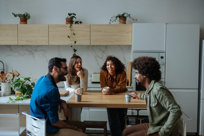 Cheerful friends laughing and talking together in the kitchen